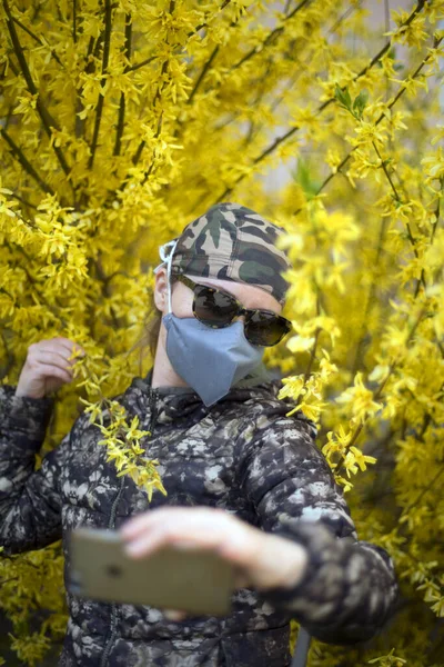 Girl in a medical mask and goggles near flowers and fresh herbs. Quarantine - strict rules of conduct in case of epidemic coronovirus Covid-19