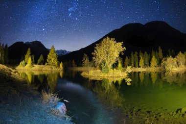 Lake in the valley Lake Morteratsch at night. Stars of the Milky Way Galaxy constellation over clear water of a reservoir in the resort area of European mountains clipart