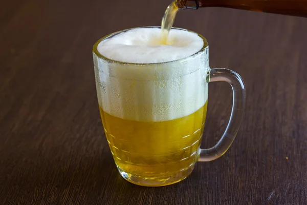Pouring beer from bottle into mug at bar — Stock Photo, Image