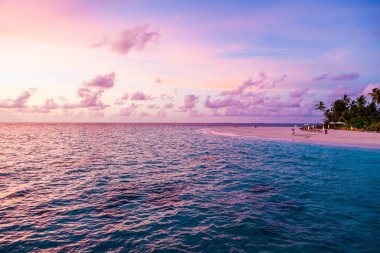 Okyanusun ortasında küçük adanın muhteşem mor günbatımı görünümü.