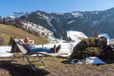 Doğal ahşap sandalye dağlar arka planında yatan güzel kız