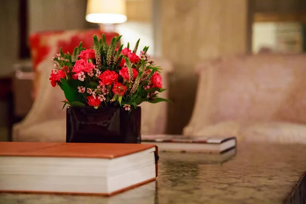 Gorgeous red flowers in a fancy room standing near a book
