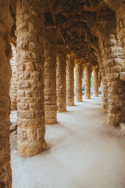 Park Guell Antoni Gaudi tarafından Barselona, İspanya, modernizm tarzında tasarlanmış taş sütunlar ağaçların arasında yapılmış 