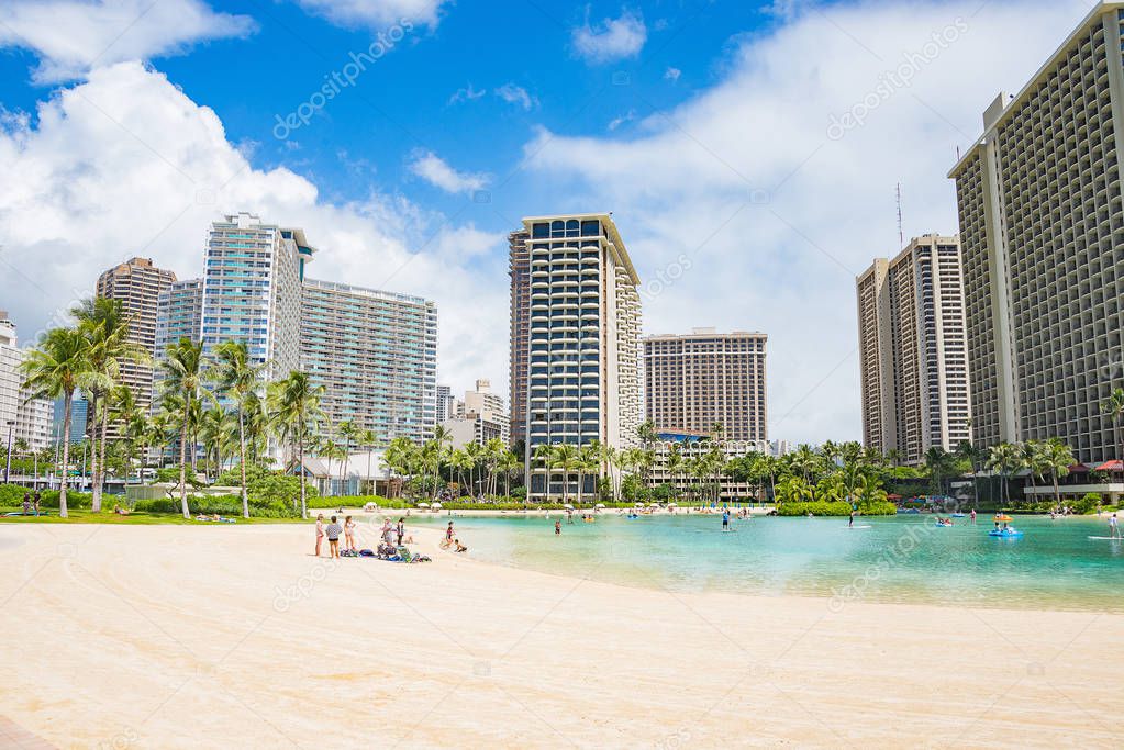 Beautiful golden Waikiki beach in Honolulu with many skyscrapers on the background.