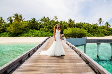 Maldivler bir iskelede uzun seksi beyaz elbise ayakta güzel gelin