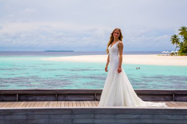 Maldivler bir iskelede uzun seksi beyaz elbise ayakta güzel gelin