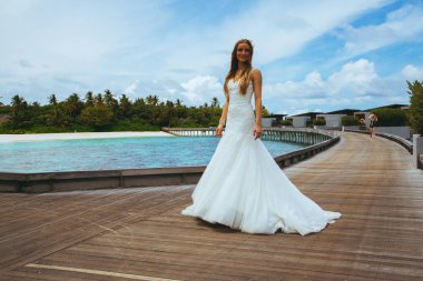 Maldivler bir iskelede uzun seksi beyaz elbise ayakta güzel gelin