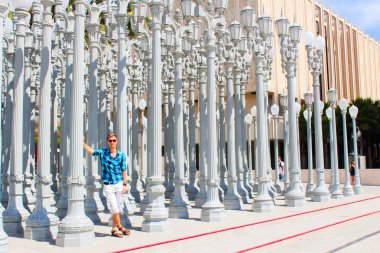 Young man standing near the Museum of modern art among lamp posts in Los Angeles, USA. clipart