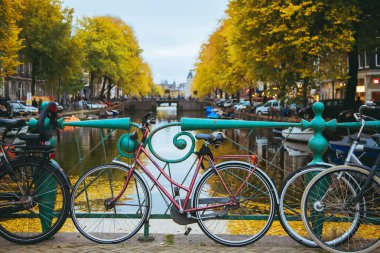 Şehir merkezinde gün batımında kanal. İnanılmaz bir Amsterdam manzaralı köprüde duran bisikletler.