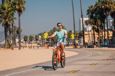 Genç adam, Los Angeles, Kaliforniya kas sahilde bir bisiklet sürme.
