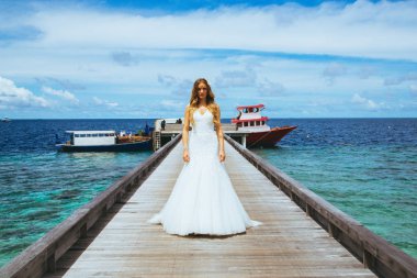 Maldivler bir iskelede uzun seksi beyaz elbise ayakta güzel gelin