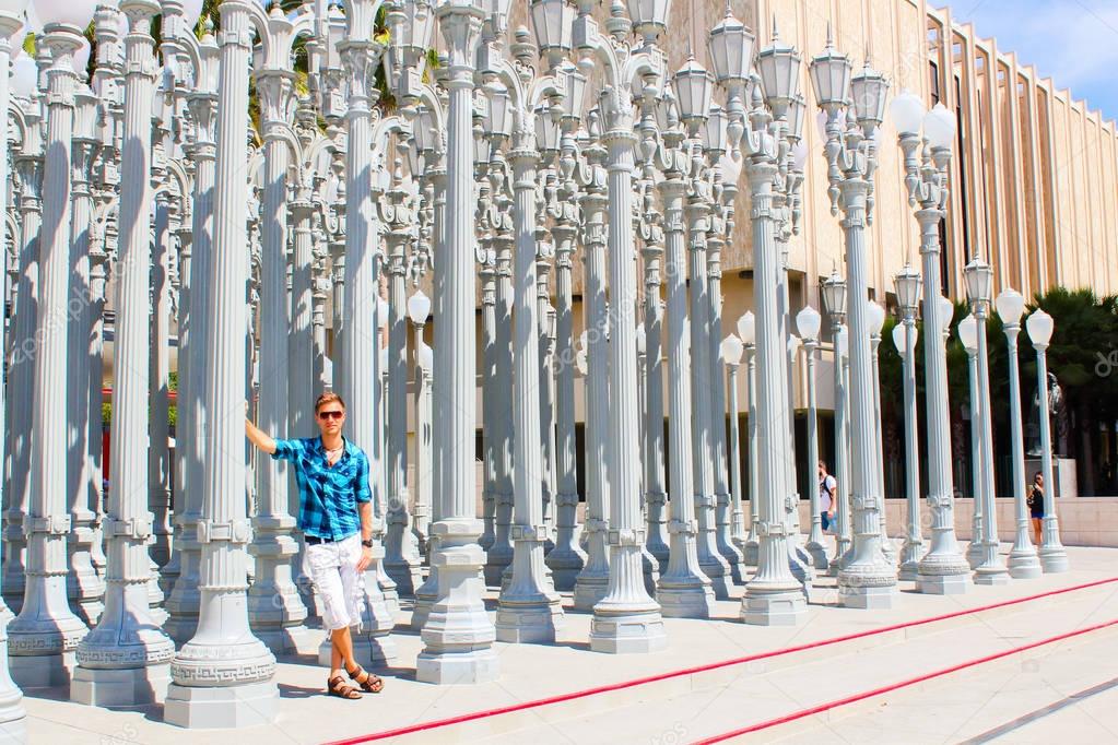 Young man standing near the Museum of modern art among lamp posts in Los Angeles, USA.