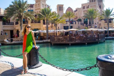 Seksi kız güzel bir yaz aylarında Medinat Souk piyasada Dubai, BAE, göl kenarında parkta duran elbise.