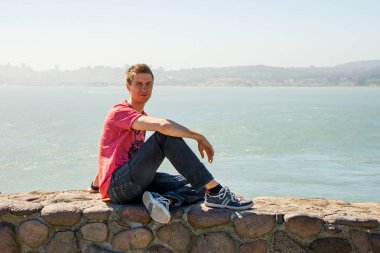 Golden Gate Köprüsü San Francisco yakınındaki su kenarında oturan genç adam