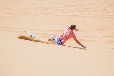 Adam sandboarding dune bir çölde aşağı