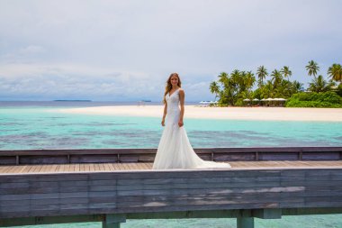 Maldivler bir iskelede uzun seksi beyaz elbise ayakta güzel gelin