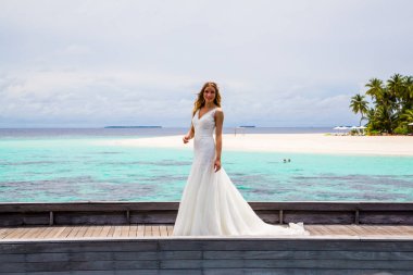 Maldivler bir iskelede uzun seksi beyaz elbise ayakta güzel gelin