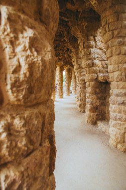 Park Guell Antoni Gaudi tarafından Barselona, İspanya, modernizm tarzında tasarlanmış taş sütunlar ağaçların arasında yapılmış