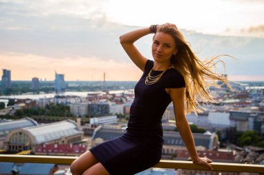 Harika bir şehir manzaralı çatı kenarında oturan güzel kız