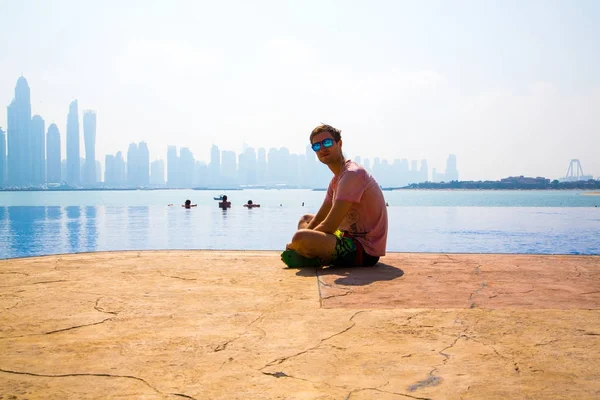 Uomo seduto vicino alla piscina a sfioro — Foto Stock