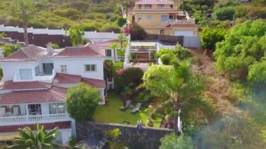 Ondan uzak uçan uçak ise Tenerife adasında villa tarafından oturan genç adam. Güzel manzara yukarıdan ada ve uçurumun kenarında villa.