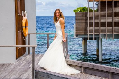 İçinde Maldivler bir iskele iskele üzerinde uzun beyaz elbise duran seksi gelin