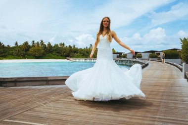 Maldivler bir iskelede uzun seksi beyaz elbise ayakta güzel gelin