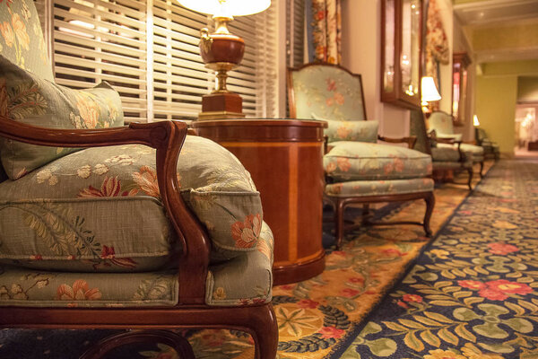 Beautiful classic soft chairs in a traditional old fashioned luxury interior with a lamp on a table.