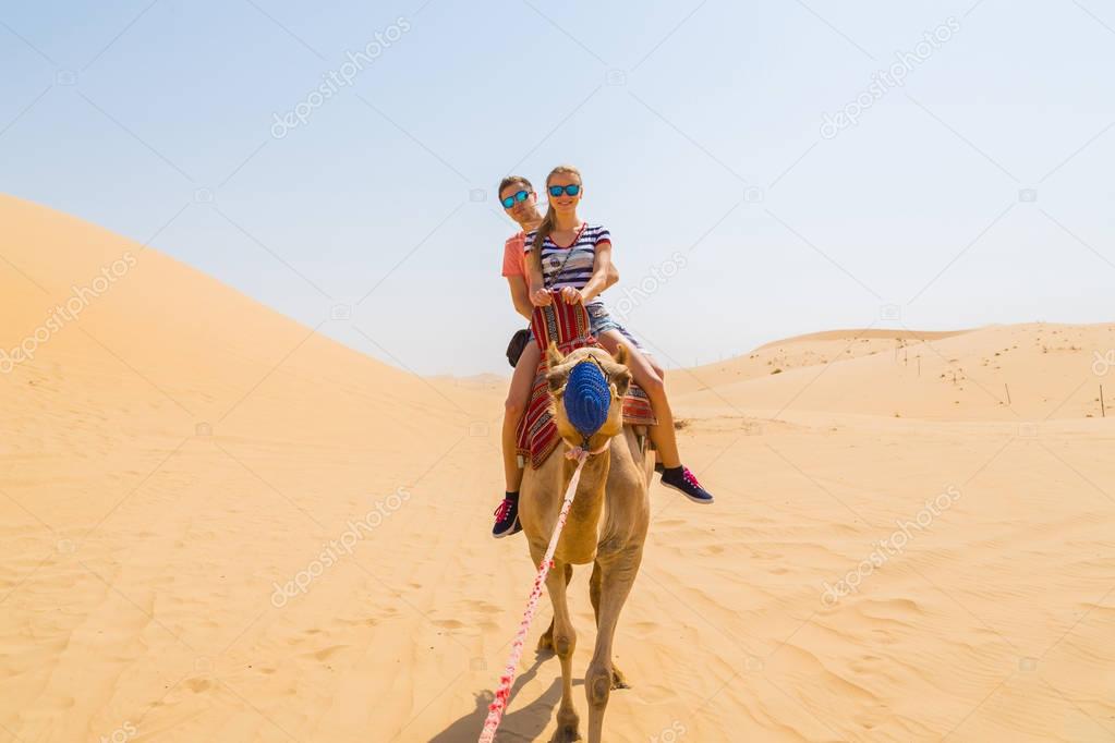 Young couple sitting on a camel in a desert