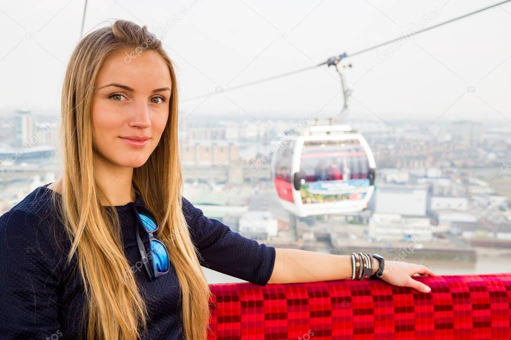 Beautiful girl sitting in a Emirates cable car over river Thames in London