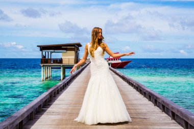 Maldivler bir iskelede uzun seksi beyaz elbise ayakta güzel gelin
