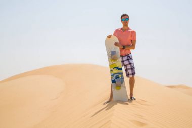 Adam bir snowboard kabuklarıyla bir çölün ortasında ile ayakta