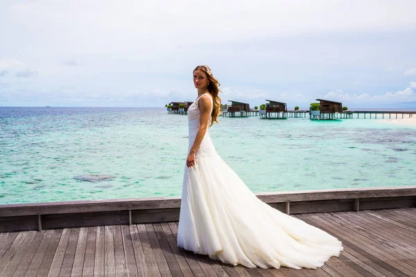 Maldivler bir iskelede uzun seksi beyaz elbise ayakta güzel gelin