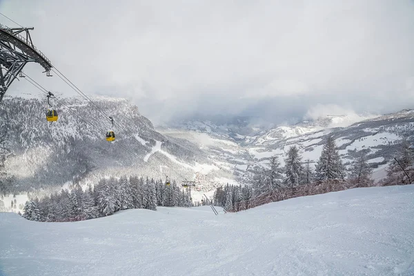 Beautiful winter day in the mountains with cable cars going to the village.