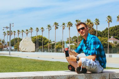 Coca Cola içme arkasında büyük bir kaya ile Los Angeles modern Sanat Müzesi tarafından oturan genç adam.