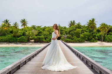 Maldivler bir iskelede uzun seksi beyaz elbise ayakta güzel gelin