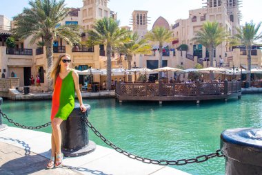 Seksi kız güzel bir yaz aylarında Medinat Souk piyasada Dubai, BAE, göl kenarında parkta duran elbise.