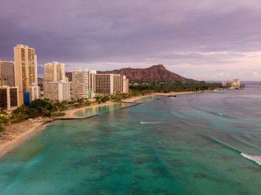 Romantik mor Waikiki beach günbatımı. Honolulu şehir manzarası ve mor elmas kafa volkan havadan görünümü yukarıdaki. Sörfçü su.