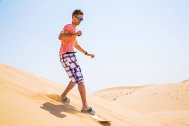 Adam sandboarding dune bir çölde aşağı