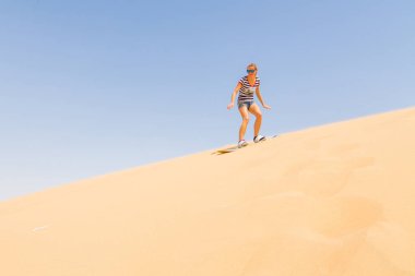 Kadın sandboarding bir çölde dune aşağı
