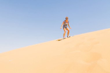 Kadın sandboarding bir çölde dune aşağı