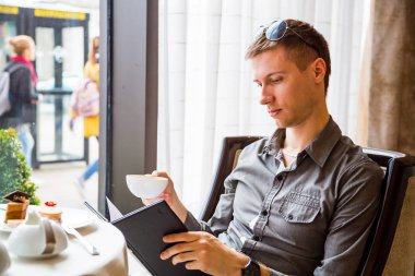 Çay içme öğleden sonra çay töreninde cam kenarında oturan genç adam