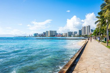 Waikiki beach Honolulu, en iyi bilinen beyaz kum ve sörf için sahil semttir. Arka planda bir Honolulu şehri ile deniz kıyısında aşağı yaya yürüyüş.