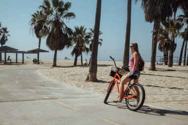 Genç güzel kız Los Angeles'taki Venedik plaj aşağı Bisiklete binmek. Kaliforniya rüya.