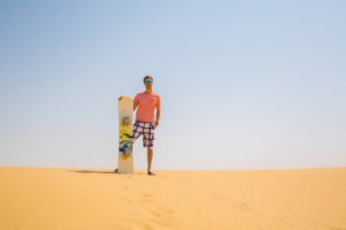 Adam bir snowboard kabuklarıyla bir çölün ortasında ile ayakta