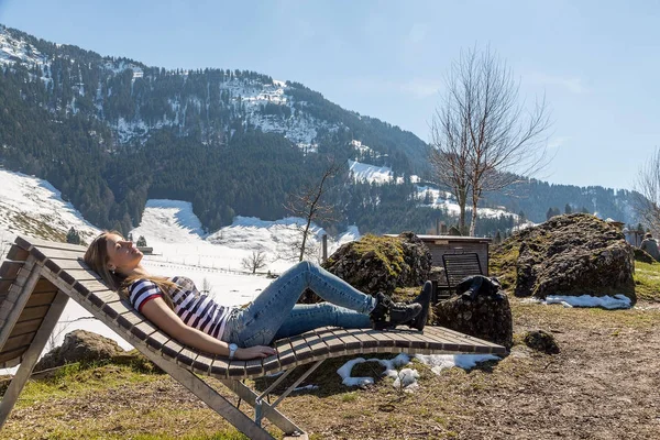 Doğal ahşap sandalye dağlar arka planında yatan güzel kız