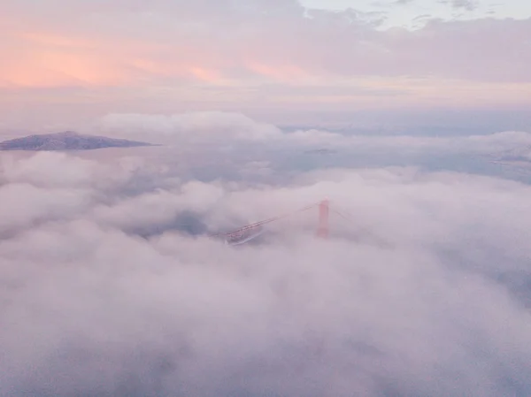 从云层上方鸟瞰旧金山金门大桥 魔幻日落时间在金门湾附近的云层上 — 图库照片
