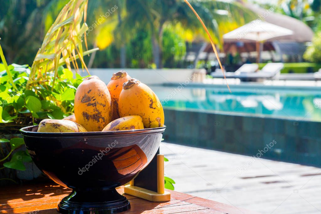 Fresh coconuts in a bowl on a table with an infinity pool on the background