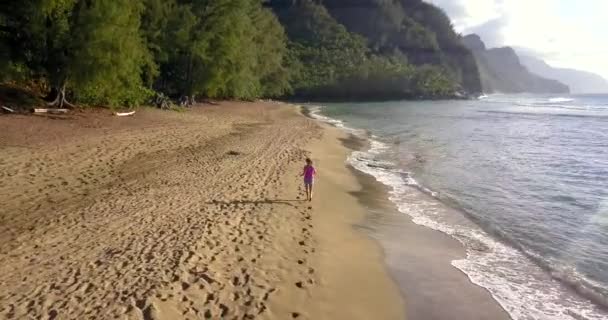 Luftaufnahme des schönen Mädchens, das die Küste von na pali auf der Insel Kauai, Hawaii, hinunterläuft 