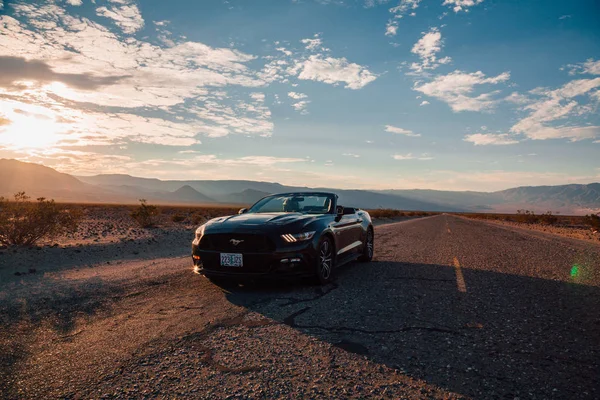 Black Ford Mustang GT convertible is parked by the infinite long road in the middle of a death valley in Nevada, USA. August 30, 2017.